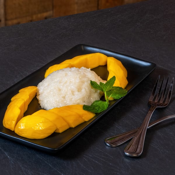 Chili Basil Thai Cuisine's mango sticky rice dessert with fresh mint on a black plate.