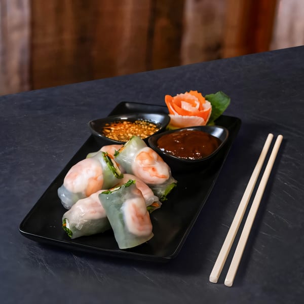 Fresh Thai spring rolls with shrimp and vegetables, served with two dipping sauces and chopsticks.