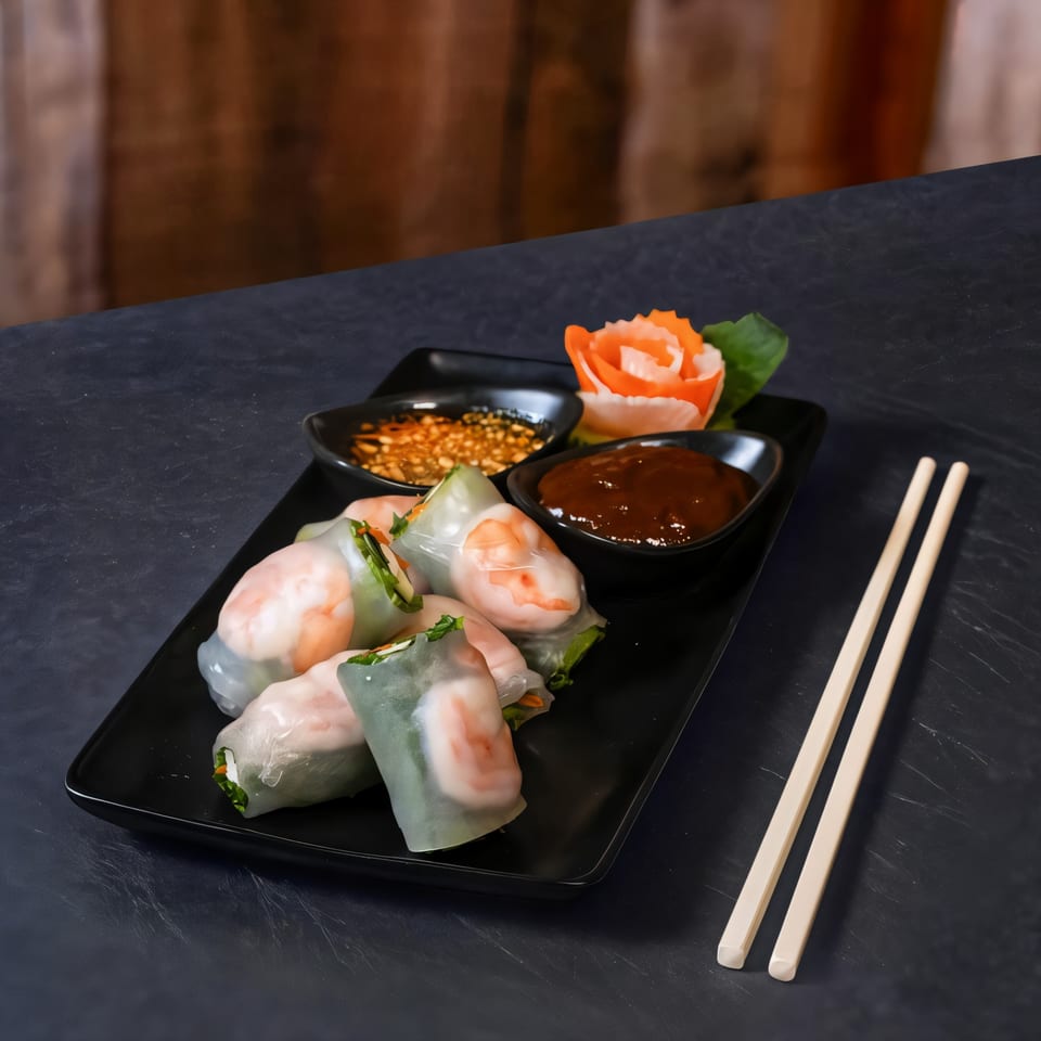 Fresh Thai spring rolls with shrimp and vegetables, served with two dipping sauces and chopsticks.