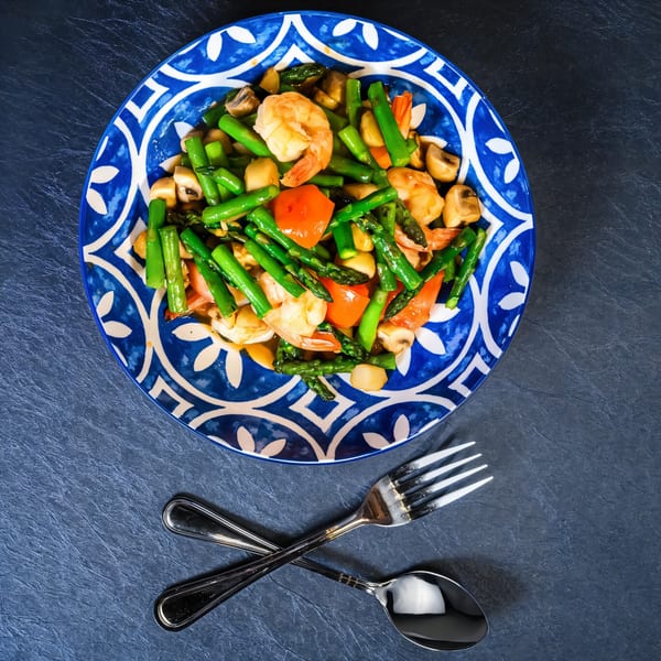 Chili Basil Thai Cuisine's shrimp, asparagus, mushrooms, and red bell peppers on a blue and white plate.